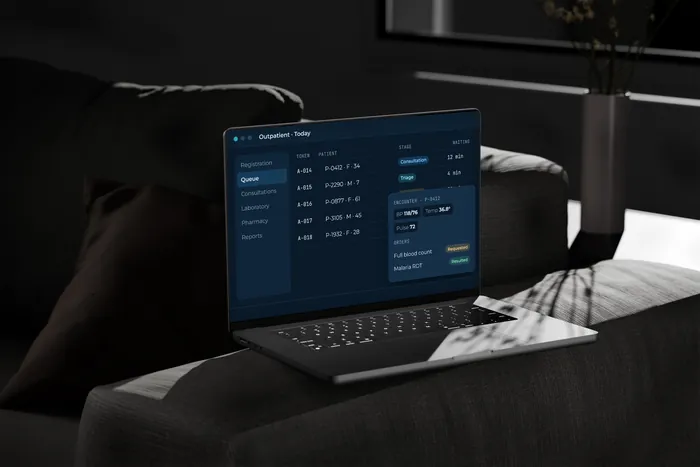 A laptop on a sofa showing an outpatient queue with sample data.